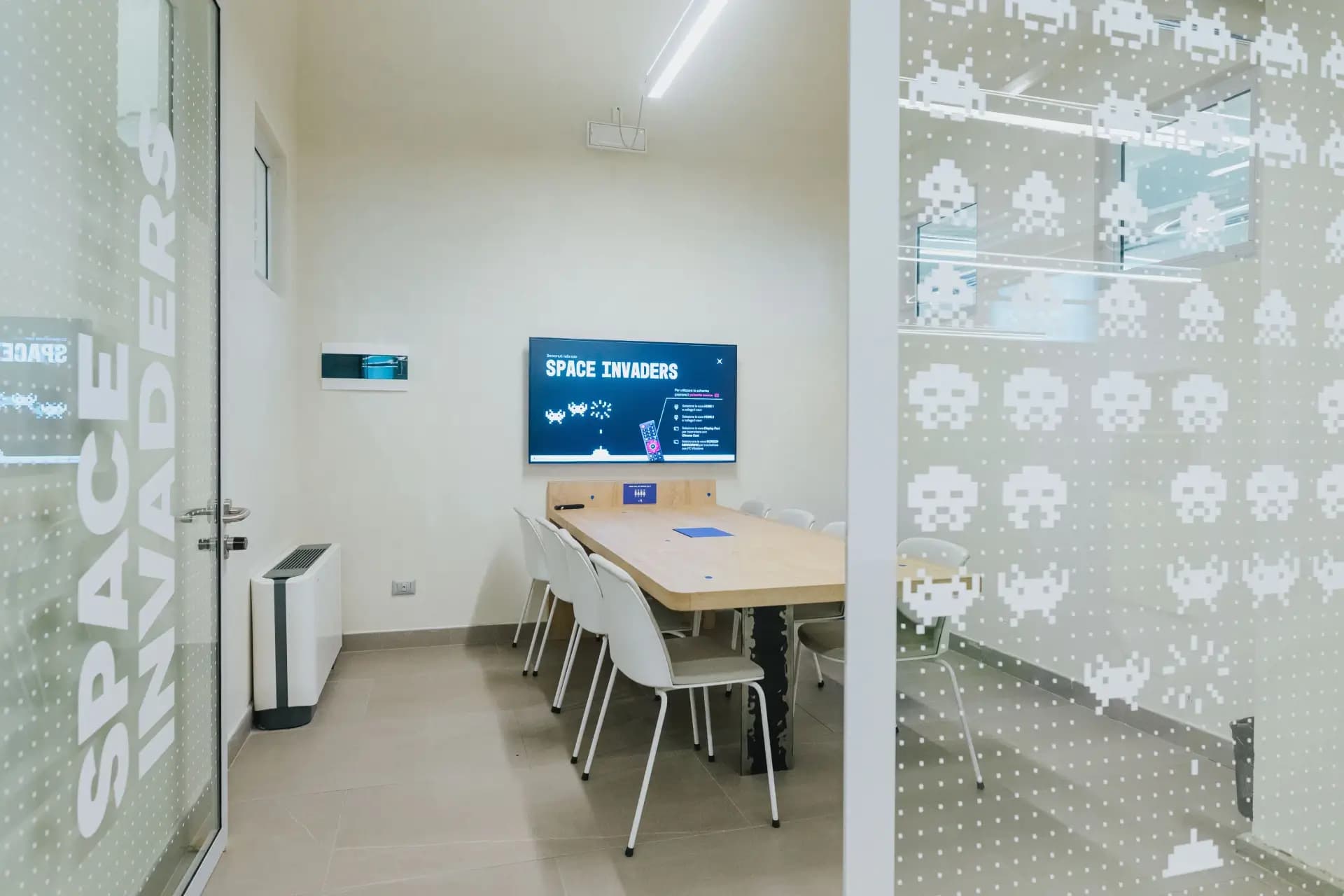 Meeting room Space Invaders a Nana Bianca, Firenze. Spazio per riunioni con arredi moderni e schermo di presentazione, perfetto per team di startup, aziende e coworking.