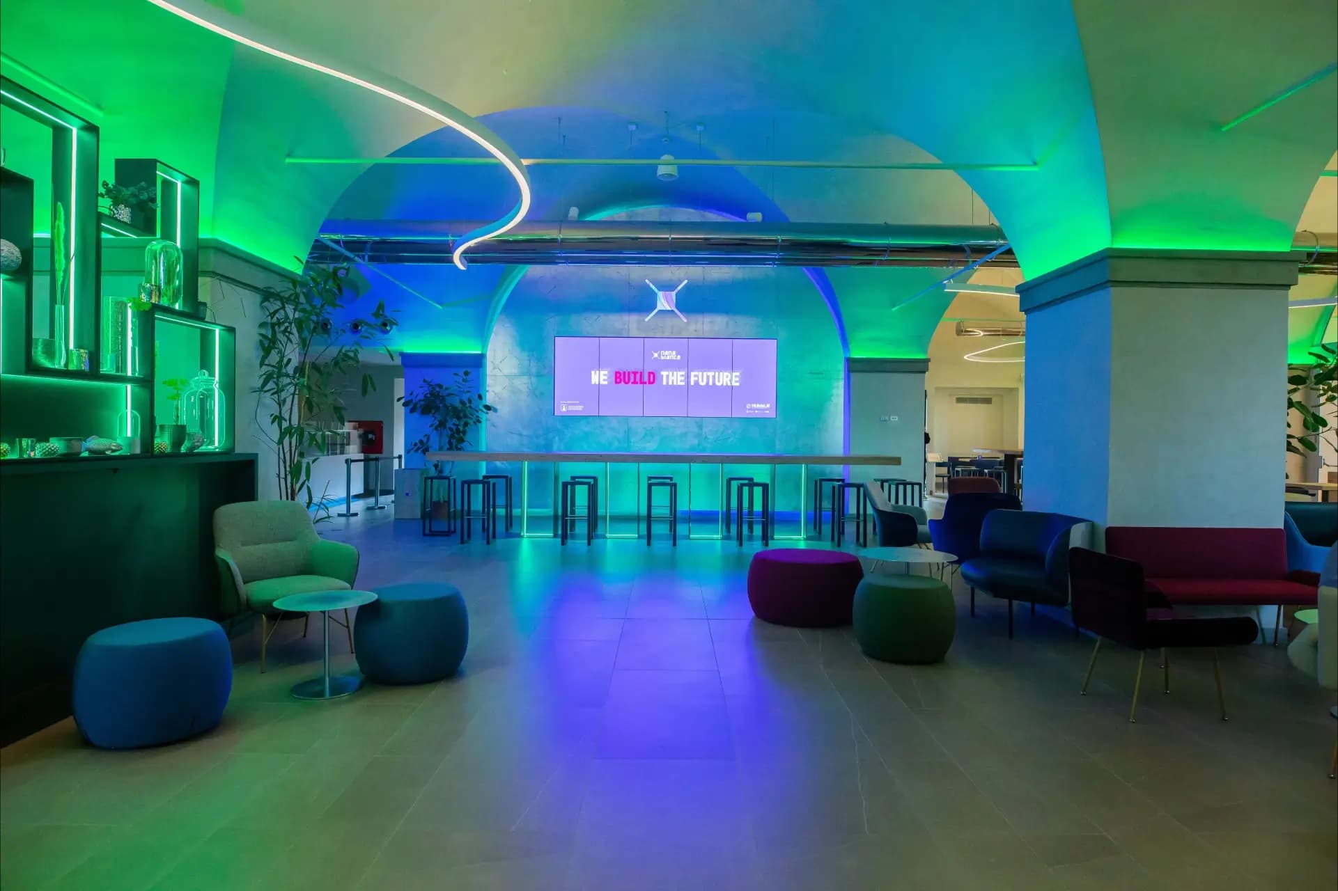 Lounge area di Nana Bianca con illuminazione LED scenografica e maxi schermo. Uno spazio perfetto per eventi aziendali, networking e presentazioni nel coworking situato a Firenze.